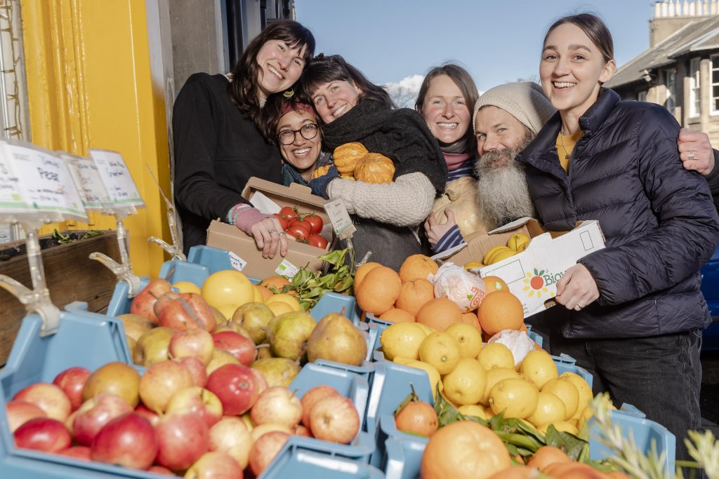 Chiara Ducker, Rosa Garmen, Beth Thomas, Sandra Flynn, Simon Delahunt and Sally Green standing behind fruit and vegetable produce at the New Leaf Co-op